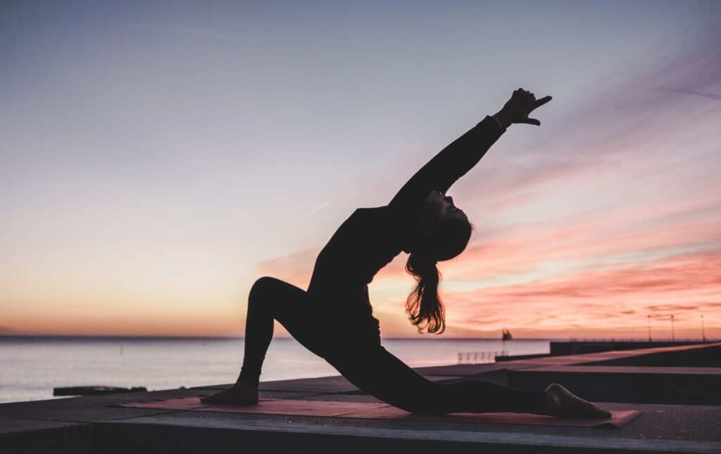 Woman practicing yoga and boosting motivation against a peaceful sunrise.