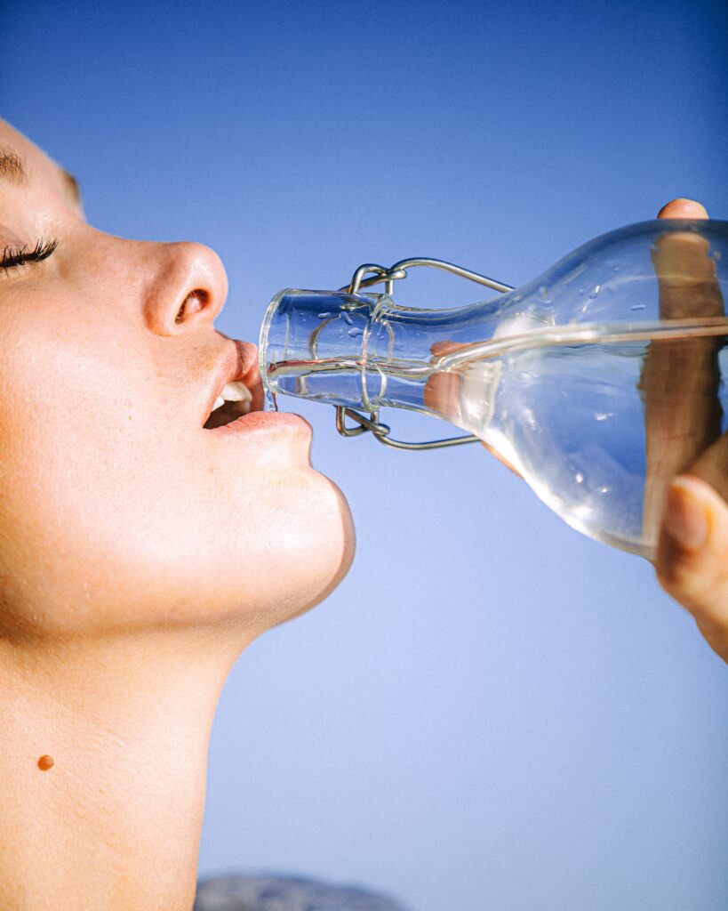 Woman Drinking Water, alleviating dehydration and providing DOMS relief.
